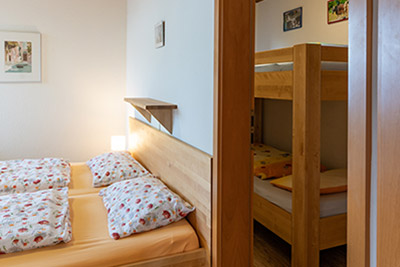 Schlafzimmer mit Doppelbett und Kinderzimmer mit Etagenbett